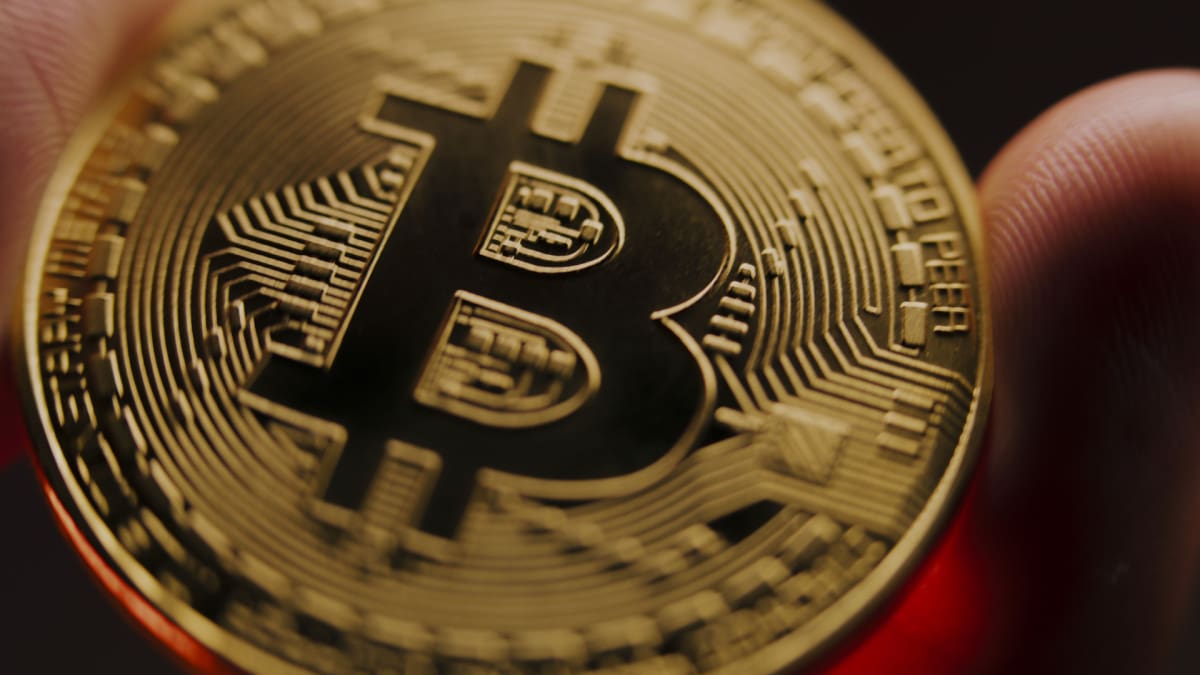 Een afbeelding van een bitcoin (BTC) die wordt vastgehouden, close-up die scherp inzoomt op de bitcoin Een afbeelding van een bitcoin (BTC) die wordt vastgehouden, close-up die scherp inzoomt op de bitcoin
